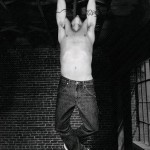 Anthony Kiedis black & white photo of him swinging from a roof beam
