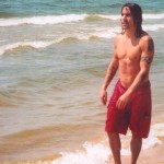 Anthony Kiedis topless on beach wearing red shorts